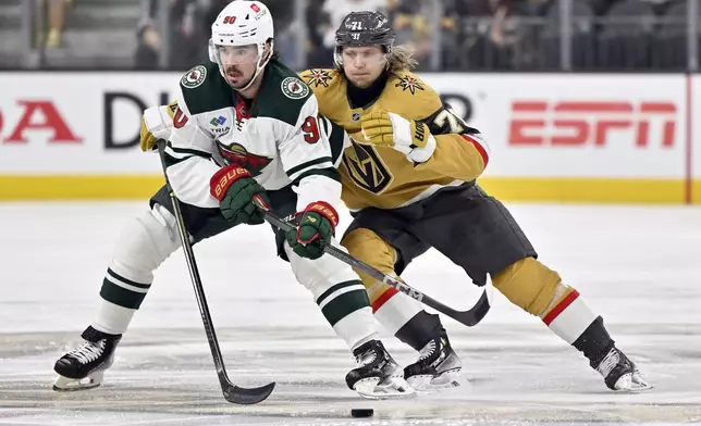 Minnesota Wild left wing Marcus Johansson (90) and Vegas Golden Knights center William Karlsson (71) vie for the puck during the second period of Game 5 of a first-round NHL hockey playoff series Tuesday, April 29, 2025, in Las Vegas. (AP Photo/David Becker)