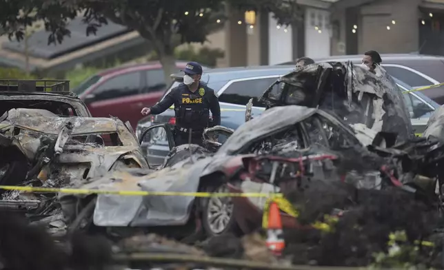 Authorities work the scene where a small plane crashed into a San Diego neighborhood, setting several homes on fire and forcing evacuations along several blocks early Thursday, May 22, 2025. (AP Photo/Gregory Bull)