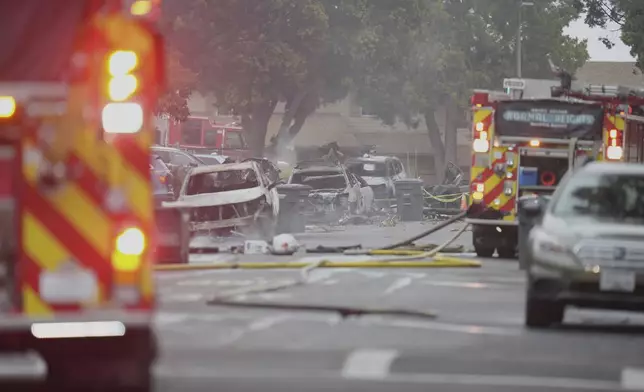 Authorities work the scene where a small plane crashed into a San Diego neighborhood, setting several homes on fire and forcing evacuations along several blocks early Thursday, May 22, 2025. (AP Photo/Gregory Bull)