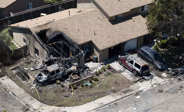 Debris covers the ground after a small plane crashed into a San Diego neighborhood, setting homes and cars on fire and forcing evacuations early Thursday, May 22, 2025. (AP Photo/William Liang)