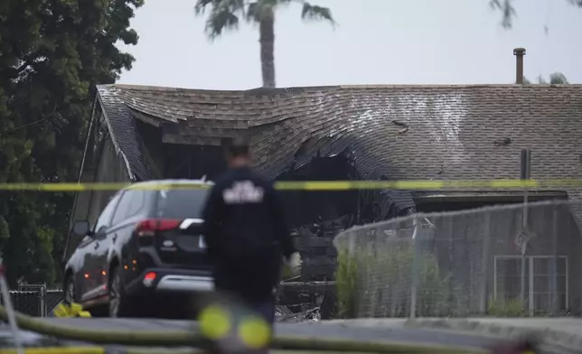 Authorities work the scene where a small plane crashed into a San Diego neighborhood, setting several homes on fire and forcing evacuations along several blocks early Thursday, May 22, 2025. (AP Photo/Gregory Bull)