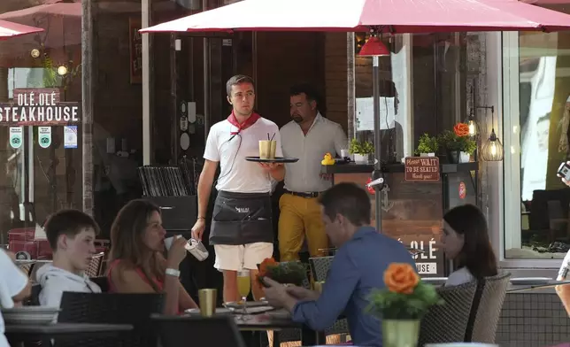 FILE - A waiter carries drinks, Friday, April 18, 2025, in Miami Beach, Fla. (AP Photo/Marta Lavandier, File)