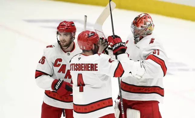 Carolina Hurricanes goaltender Frederik Andersen, right, celebrates with defenseman Shayne Gostisbehere (4) and defenseman Sean Walker (26) after Game 5 of a second-round NHL hockey playoff series against the Washington Capitals Thursday, May 15, 2025, in Washington. (AP Photo/Nick Wass)