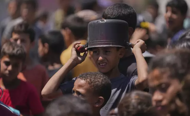A young Palestinian waits to collect donated food at a food distribution kitchen in Deir al-Balah, Gaza Strip, Friday, May 30, 2025. (AP Photo/Abdel Kareem Hana)