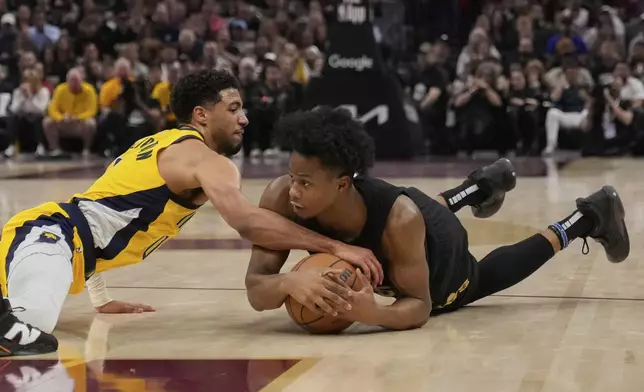Indiana Pacers guard Tyrese Haliburton, left, and Cleveland Cavaliers forward Isaac Okoro scramble for a loose ball during the first half in Game 5 of an Eastern Conference semifinal NBA basketball playoff Tuesday, May 13, 2025, in Cleveland. (AP Photo/Sue Ogrocki)