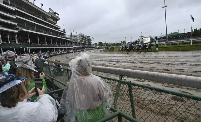 Race fans watch horses pass at Churchill Downs before the 151st running of the Kentucky Derby horse race Saturday, May 3, 2025, in Louisville, Ky. (AP Photo/Jon Cherry)