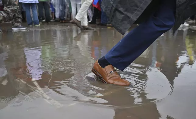 A race fan walks through a puddle at Churchill Downs before the 151st running of the Kentucky Derby horse race Saturday, May 3, 2025, in Louisville, Ky. (AP Photo/Jon Cherry)