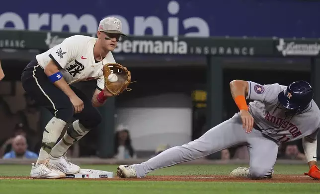 Houston Astros' Cam Smith (11) reaches third base against a throw to Texas Rangers third baseman Josh Jung, left, during the seventh inning of a baseball game, Friday, May 16, 2025, in Arlington, Texas. (AP Photo/LM Otero)