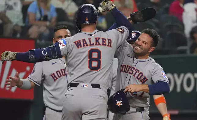 Houston Astros' Christian Walker (8) celebrates after his home run with teammate Jose Altuve, right, during the seventh inning of a baseball game against the Texas Rangers, Friday, May 16, 2025, in Arlington, Texas. (AP Photo/LM Otero)