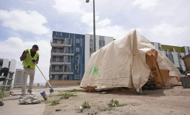 Jay Joshua cleans up around a homeless encampment where he currently lives, Monday, May 12, 2025, in Los Angeles. (AP Photo/Damian Dovarganes)