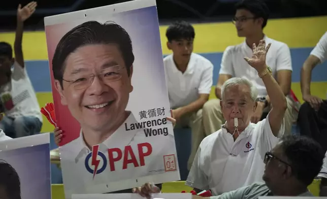 Supporters of ruling party People's Action Party (PAP) cheer as they hold a picture of Prime Minister Lawrence Wong's as they wait for results of the general election at a stadium in Singapore, Saturday, May 3, 2025. (AP Photo/Vincent Thian)