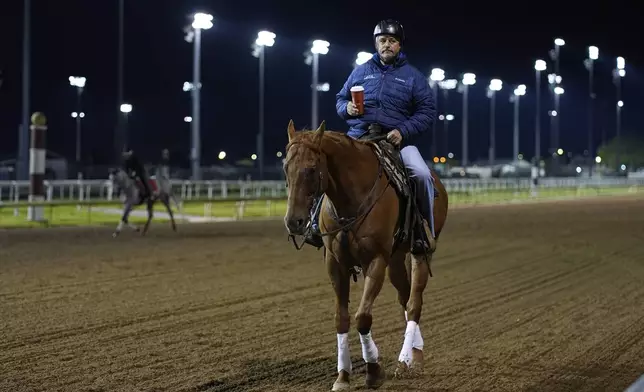Trainer Steve Asmussen rides back to his barn after watching a workout at Churchill Downs Monday, April 28, 2025, in Louisville, Ky. (AP Photo/Charlie Riedel)
