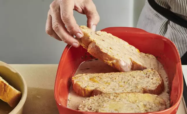 Challah slices are dipped into an egg custard to make French toast in New York. (Cheyenne Cohen via AP)