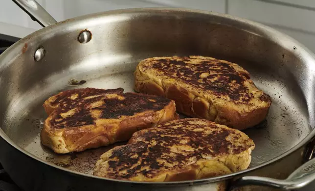 Challah slices, dipped into an egg custard, are fried in a skillet to make French toast in New York. (Cheyenne Cohen via AP)