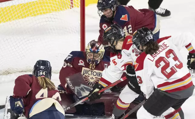 Ottawa Charge's Rebecca Leslie (second right) and Jocelyne Larocque (23) battle for the rebound in front of Montreal Victoire goaltender Ann-Renee Desbiens (35) during second period PWHL playoff hockey action in Laval, Que., on Thursday, May 8, 2025. (Christinne Muschi/The Canadian Press via AP)