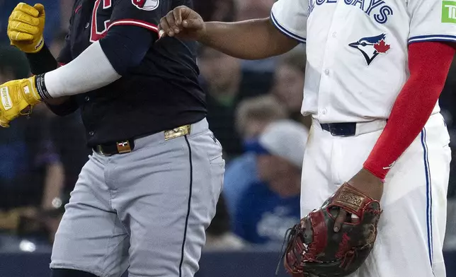 Cleveland Guardians Carlos Santana, left, jokes with Toronto Blue Jays first baseman Vladimir Guerrero Jr during the first inning of a baseball game in Toronto, Saturday, May 3, 2025. (Jon Blacker/The Canadian Press via AP)