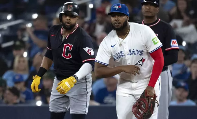 Cleveland Guardians' Carlos Santana, left, jokes with Toronto Blue Jays first baseman Vladimir Guerrero Jr during the first inning of a baseball game in Toronto, Saturday, May 3, 2025. (Jon Blacker/The Canadian Press via AP)