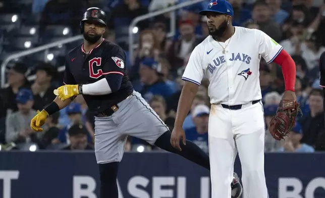 Cleveland Guardians' Carlos Santana, left, jokes with Toronto Blue Jays first baseman Vladimir Guerrero Jr during the first inning of a baseball game in Toronto, Saturday, May 3, 2025. (Jon Blacker/The Canadian Press via AP)