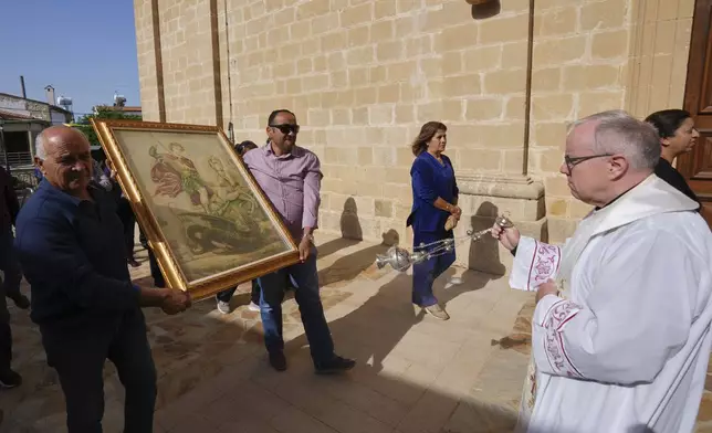 A priest swings a senser at an icon of St. George during a traditional procession on the saint's Feast Day outside St. George Church in the Maronite village of Kormakitis in the breakaway north of the ethnically divided Cyprus on Wednesday, April 23, 2025. (AP Photo/Petros Karadjias)