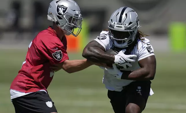 Las Vegas Raiders' quarterback Cam Miller hands off a ball to Ashton Jeanty during an NFL football rookie mini camp Friday, May 9, 2025, in Henderson, Nev. (AP Photo/John Locher)