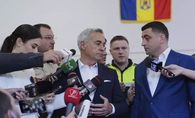 Presidential candidate George Simion, right, and Calin Georgescu, winner of the first round of last year's annulled election, speak to media after casting their votes in the second round of the country's presidential election redo in Mogosoaia, Romania, Sunday, May 18, 2025. (AP Photo/Andreea Alexandru)