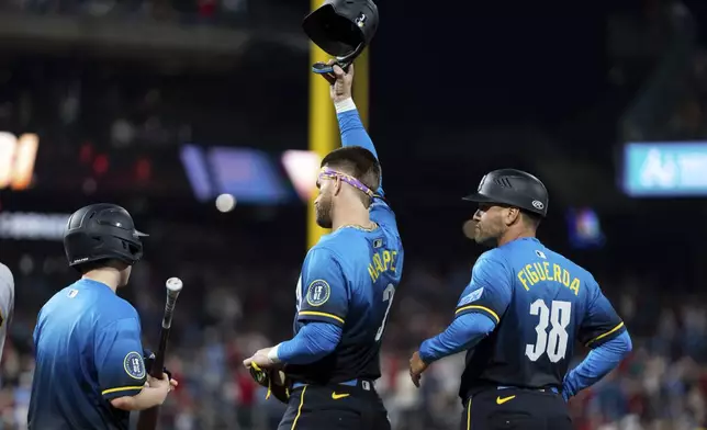 Philadelphia Phillies' Bryce Harper, center, reacts to the crowd after recording his 1000th RBI during the fifth inning of a baseball game against the Pittsburgh Pirates, Friday, May 16, 2025, in Philadelphia. (AP Photo/Chris Szagola)
