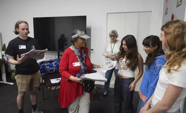 Claire Smith, founding executive director of Temple University's sports media center, center, and Samuel O'Neal, left, editor-in-chief of the Temple News, deliver copies of the Palisades High School newspaper to staff, Wednesday, May 14, 2025, in Santa Monica, Calif. (AP Photo/Marcio Jose Sanchez)