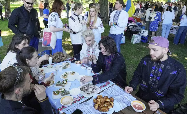 Eurovision competitor band Ziferblat from Ukraine eats traditional food during a family meeting of Ukrainian people in a park in Basel as part of the 69th Eurovision Song Contest week, in Basel, Switzerland, Thursday, May 15, 2025. (AP Photo/Martin Meissner)