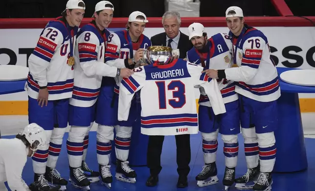 Team USA players hold the trophy and the jersey of the late Johnny Gaudreau after winning the final match between United States and Switzerland at the ice hockey world championships in Stockholm, Sweden, Sunday, May 25, 2025. (AP Photo/Petr David Josek)
