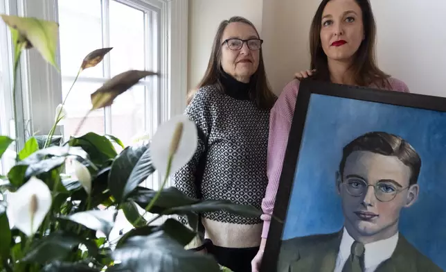 Cathy Votaw, 69, left, and her daughter Anna Eisenberg, pose with a painting of Votaw's father, Albert Votaw, portrayed as a young man in the 1940's, Thursday, Feb. 27, 2025, at their home in Washington. (AP Photo/Jacquelyn Martin)