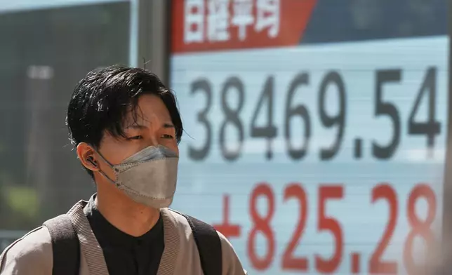 A person walks in front of an electronic stock board showing Japan's Nikkei index at a securities firm Tuesday, May 13, 2025, in Tokyo. (AP Photo/Eugene Hoshiko)