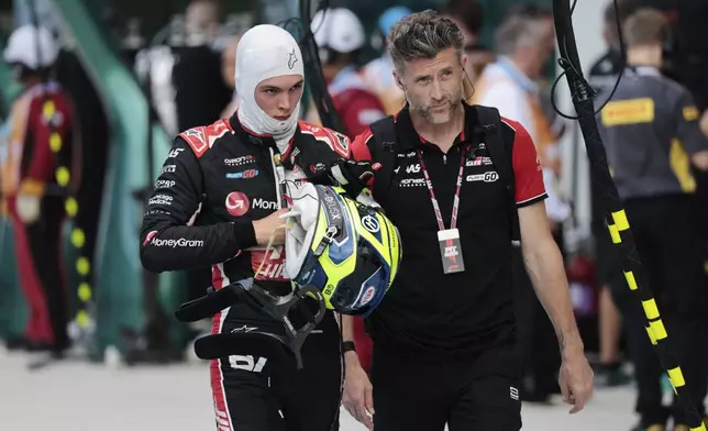 Haas driver Oliver Bearman of Britain, left, walks through the pit area after being eliminated during the qualifying session for the Formula One Miami Grand Prix auto race at the International Autodrome, Saturday, May 3, 2025, in Miami Gardens, Fla. (Shawn Thew/Pool Photo via AP)