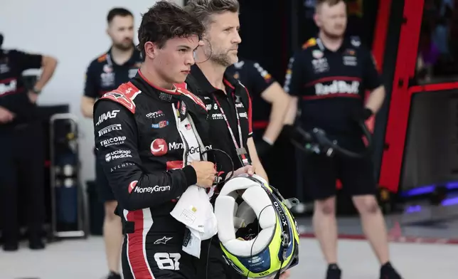 Haas driver Oliver Bearman of Britain, left, walks through the pit area after being eliminated during the qualifying session for the Formula One Miami Grand Prix auto race at the International Autodrome, Saturday, May 3, 2025, in Miami Gardens, Fla. (Shawn Thew/Pool Photo via AP)