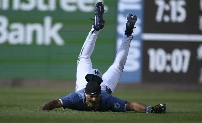 Washington Nationals right fielder Daylen Lile slides on the grass after he made a catch on a fly ball hit by San Francisco Giants' Matt Chapman for the out during the ninth inning of a baseball game, Saturday, May 24, 2025, in Washington. (AP Photo/Nick Wass)