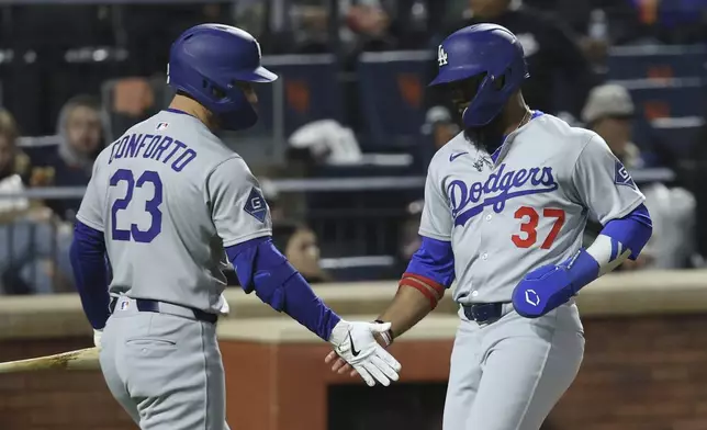 Los Angeles Dodgers' Teoscar Hernández, right, reacts after scoring on a single hit by Andy Pages with Michael Conforto, left, during the fifth inning of a baseball game against the New York Mets, Friday, May 23, 2025, in New York. (AP Photo/Pamela Smith)