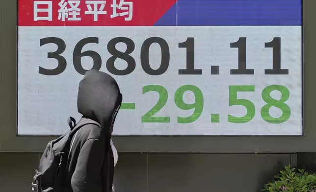 A person walks in front of an electronic stock board showing Japan's Nikkei index at a securities firm Wednesday, May 7, 2025, in Tokyo. (AP Photo/Eugene Hoshiko)