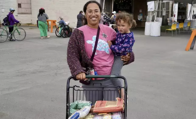 Alameda resident Christina Santamaria stands outside the Alameda Food Bank with groceries and her daughter in Alameda, Calif. on Friday, April 25, 2025. (AP Photo/Terry Chea)