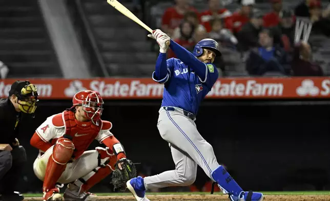 Toronto Blue Jays' Anthony Santander, right, follows through to hit a solo home run next to Los Angeles Angels catcher Logan O'Hoppe during the eighth inning of a baseball game in Anaheim, Calif., Tuesday, May 6, 2025. (AP Photo/Alex Gallardo)