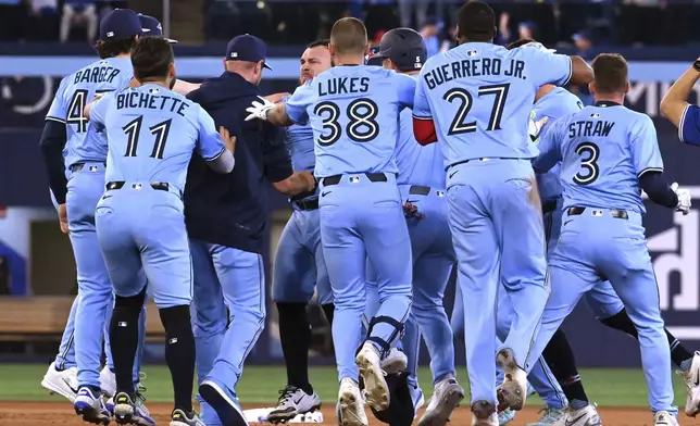 Toronto Blue Jays' Alejandro Kirk, centre facing, celebrates with teammates after hitting a walk-off RBI single in tenth inning American League baseball action to defeat the Boston Red Sox in Toronto on Wednesday, April 30, 2025. (Jon Blacker/The Canadian Press via AP)