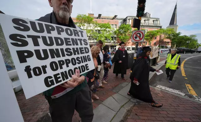 Students cross into Harvard yard passing protesters as Harvard University holds its commencement, Thursday, May 29, 2025 in Cambridge, Mass. (AP Photo/Charles Krupa)