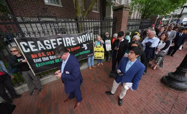 Protesters stand outside the gates of Harvard yard as guests line up for commencement ceremonies, Thursday, May 29, 2025 in Cambridge, Mass. (AP Photo/Charles Krupa)