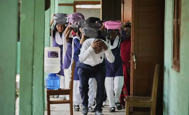 School students and teachers participate in a mock drill trained by civil defence members to respond in case of attack in Guwahati, India, Saturday, May 10, 2025 amid rising fears of wider conflict following India's strikes in Pakistan. (AP Photo/Anupam Nath)