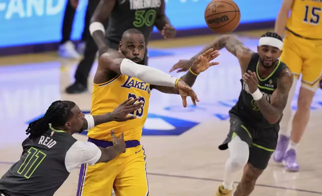 Los Angeles Lakers forward LeBron James, center, passes the ball as Minnesota Timberwolves center Naz Reid, left, and guard Nickeil Alexander-Walker defend during the second half in Game 5 of an NBA basketball first-round playoff series Wednesday, April 30, 2025, in Los Angeles. (AP Photo/Mark J. Terrill)