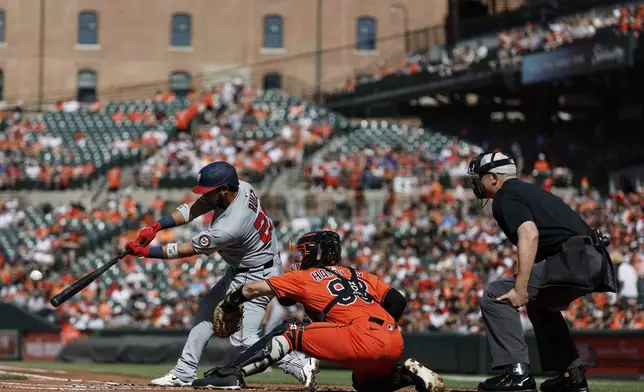 Washington Nationals' Keibert Ruiz, left, hits an RBI double off Baltimore Orioles pitcher Kyle Gibson during the first inning of a baseball game in Baltimore, Saturday, May 17, 2025. (AP Photo/Terrance Williams)