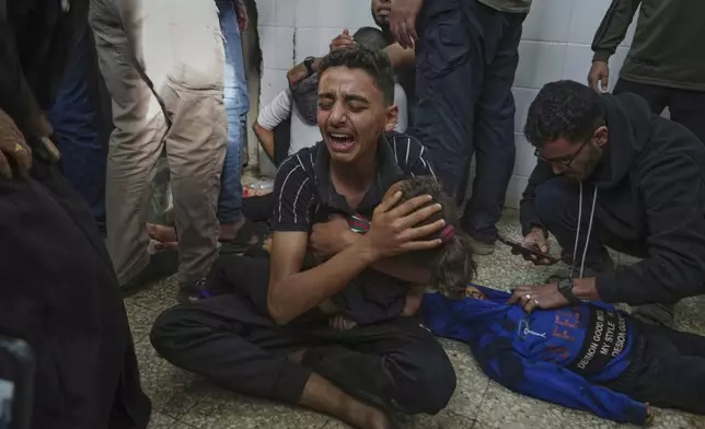 FILE - Mohammed Abed, center, weeps as he holds the body of his younger sister, Massa , 4, who was killed in an Israeli army airstrike on the Gaza Strip, at the morgue of Al-Aqsa Hospital in Deir al-Balah, Gaza, Sunday, April 27, 2025. (AP Photo/Abdel Kareem Hana, File)