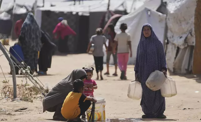 Displaced Palestinians fill jerrycans with water from a pipe at a tent camp in Khan Younis, Gaza Strip, on Sunday, May 11, 2025. (AP Photo/Abdel Kareem Hana)