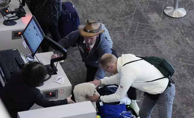 A traveler takes an item out of his suitcase while attempting to check-in his luggage at San Francisco International Airport ahead of the Memorial Day holiday weekend in San Francisco, Thursday, May 22, 2025. (AP Photo/Godofredo A. Vásquez)