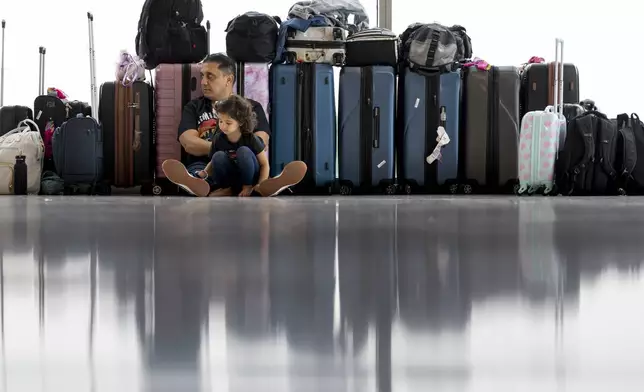 FILE - Samuel Tadros and his daughter Serenity 3, sit with the family's bags after their flight to New York was cancelled at the Nashville international Airport Thursday, May 23, 2024, in Nashville, Tenn., ahead of Memorial Day. (AP Photo/George Walker IV, File)