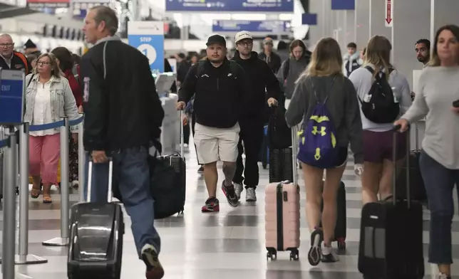Travelers carry their luggage through at O'Hare International Airport in Chicago, Friday, May 23, 2025. (AP Photo/Nam Y. Huh)