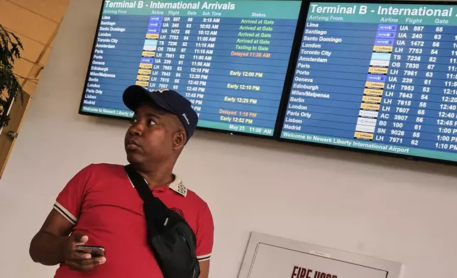 A passenger waits near an arrivals board at Newark Liberty International Airport, in New Jersey, Friday, May 23, 2025. (AP Photo/Richard Drew)